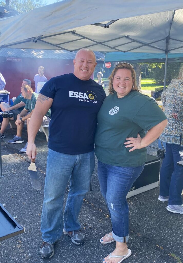 2 ESSA employees pose near a grill at a Rotary Annual Poker Run.
