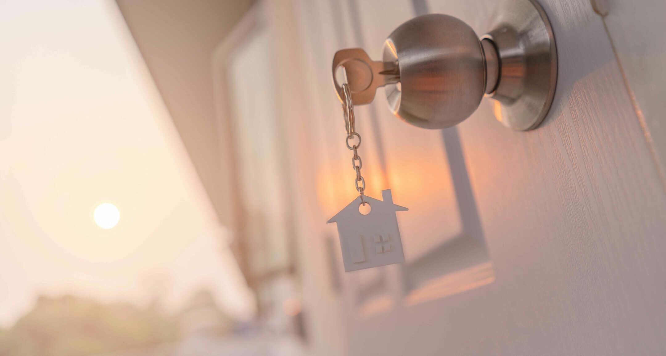 Key in doorknob with house keychain dangling.