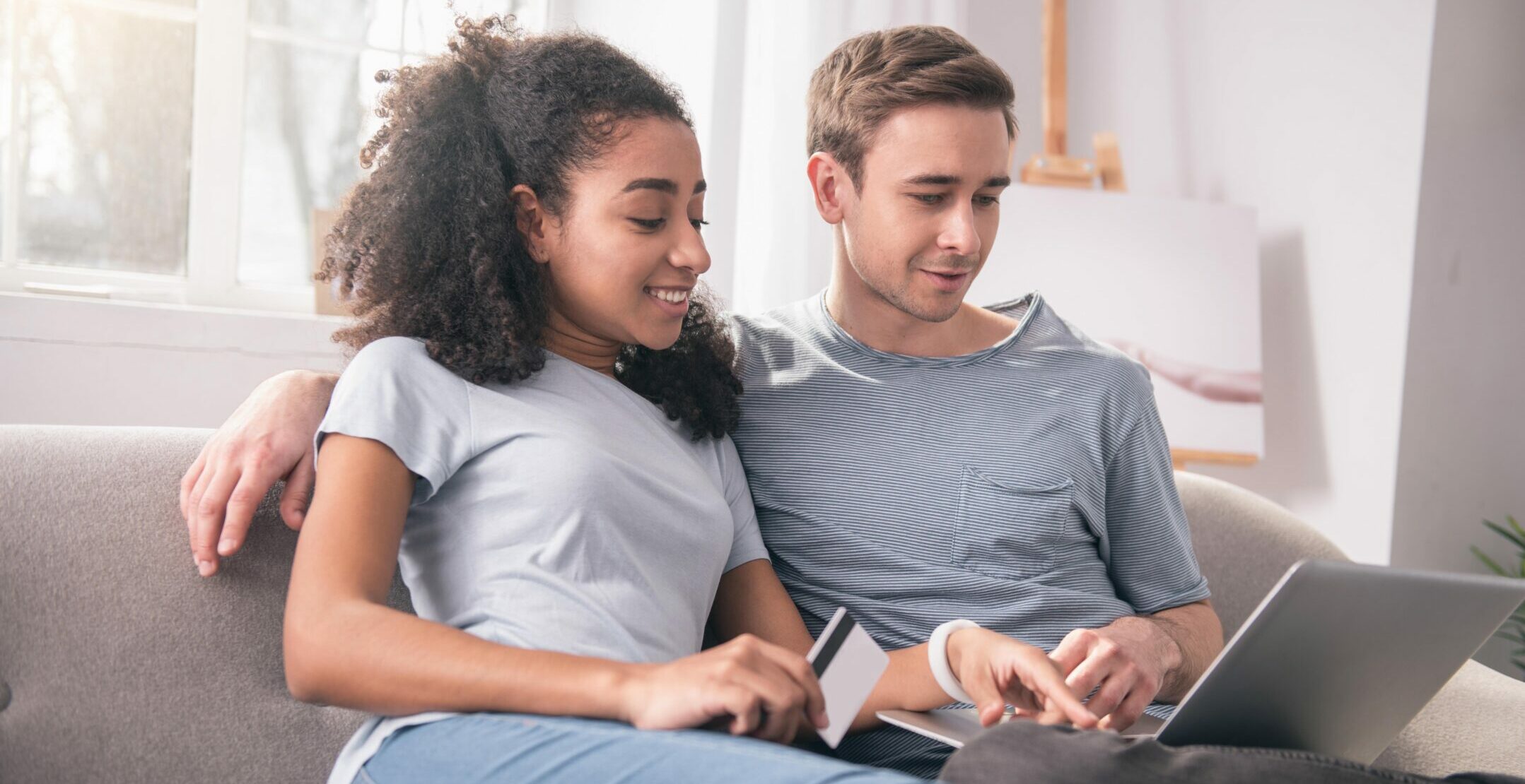 Joint activity. Joyful young couple sitting in front of the laptop while doing online shopping together