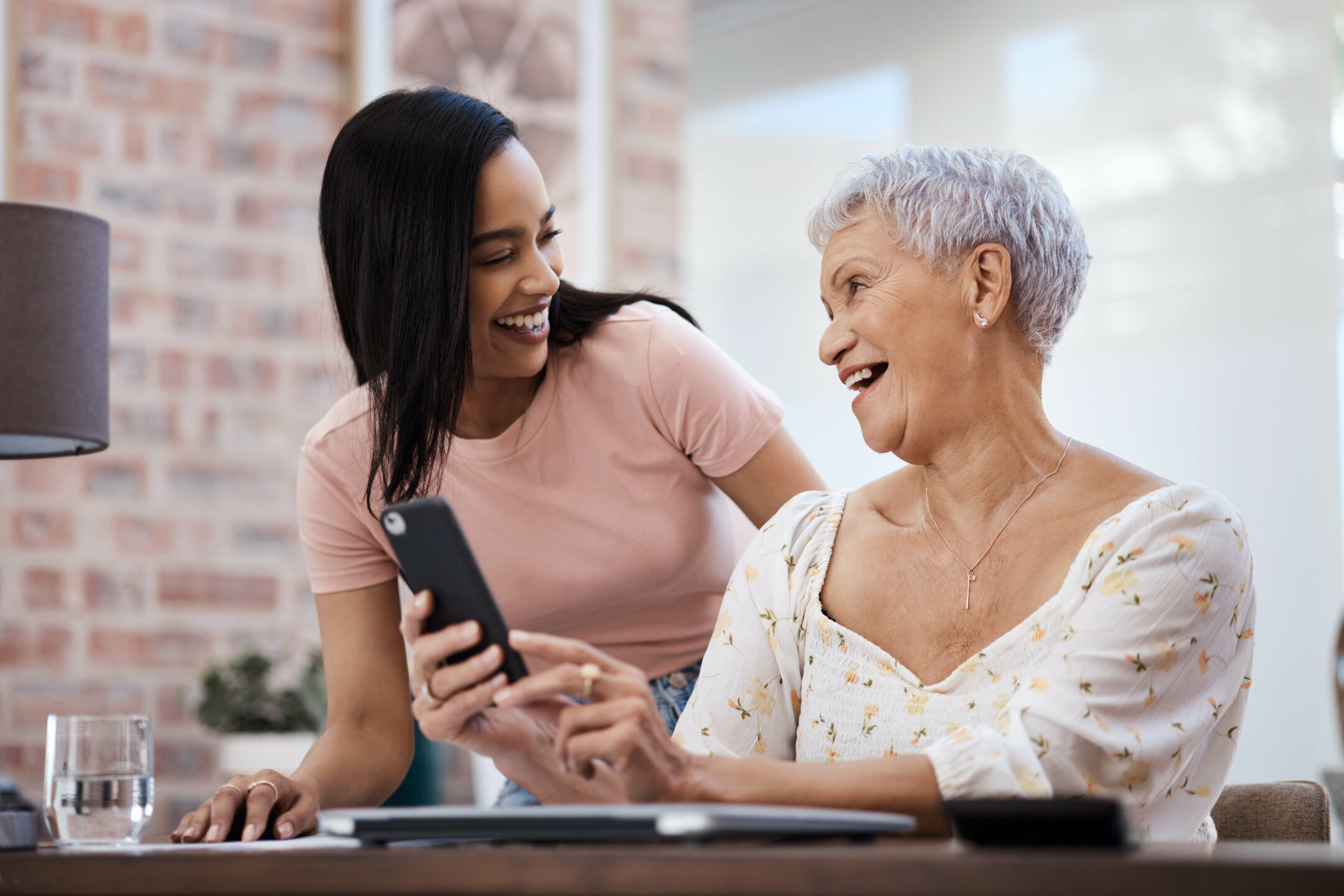 The smart way to invest those savings. Shot of a young woman using a smartphone with her elderly mother while going through finances at home.